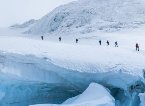 An expedition of hikers in the snowy steep mountains