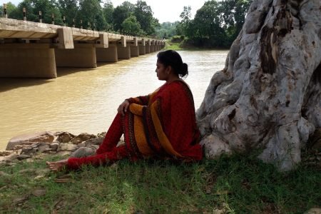 woman-sitting-lakeshore-against-tree